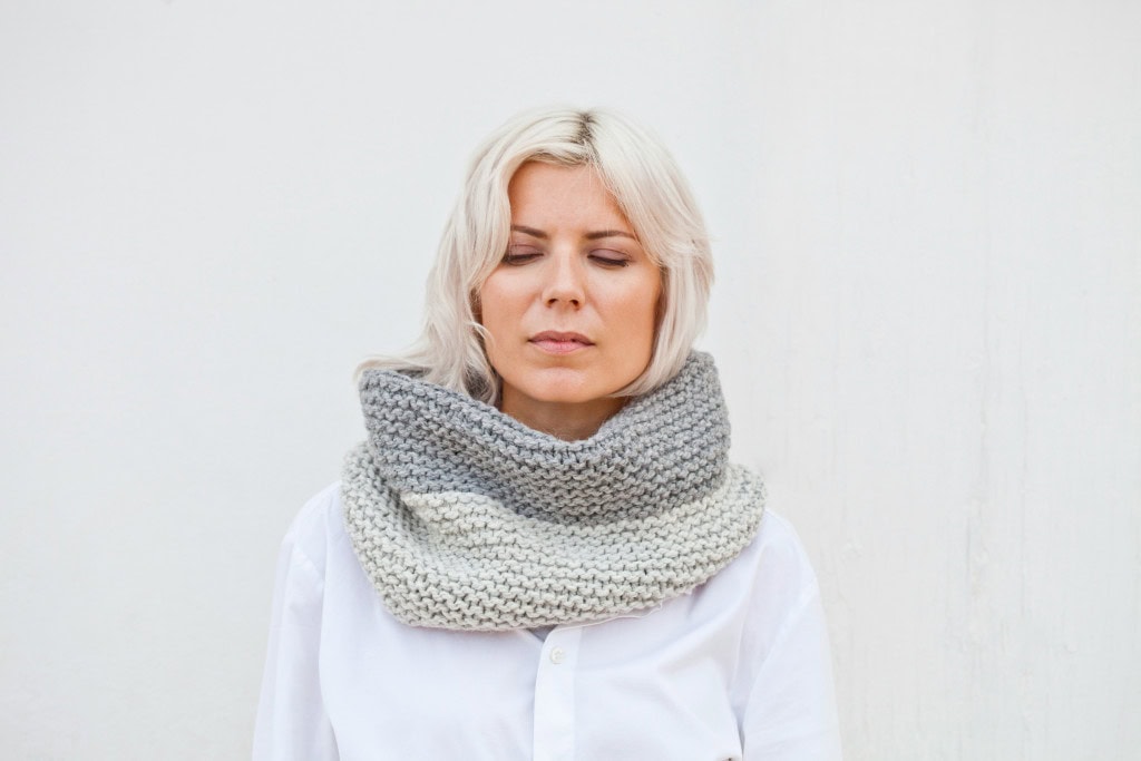 Middle-aged woman with short blonde hair wearing a knitted scarf with eyes closed, representing the contemplative journey through perimenopause.