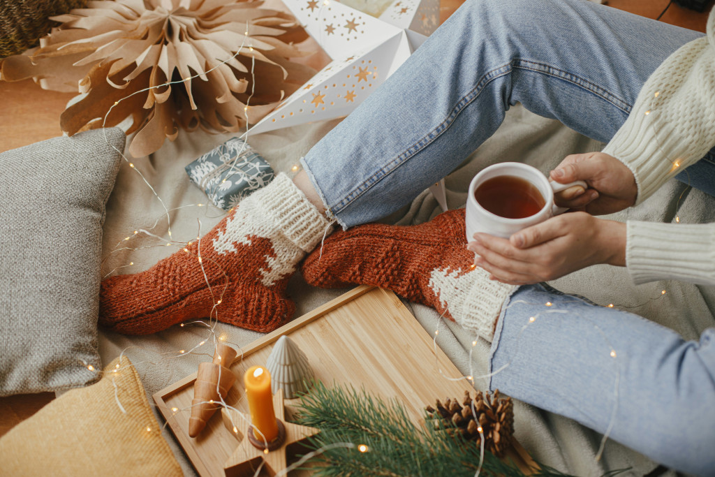 woman relaxing with coffee while sitting among Christmas wrapping