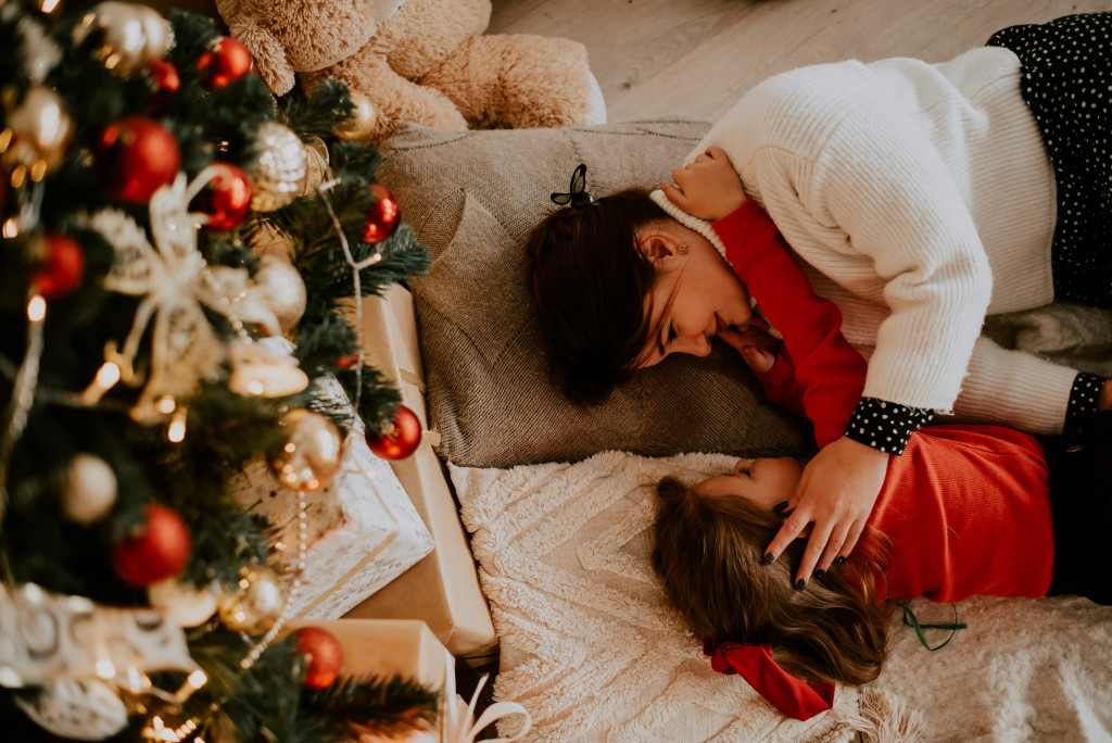 tired mother and child lying under Christmas tree 