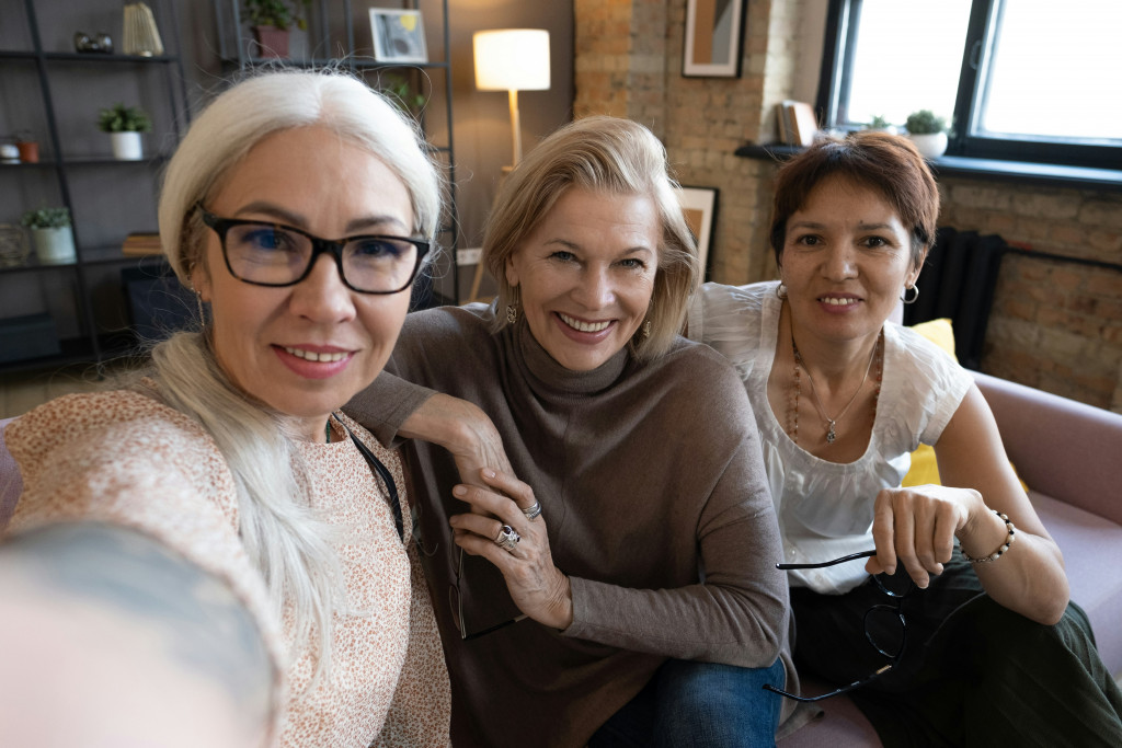 A group of women smile together while taking a selfie, representing the importance of community and sharing experiences while navigating health changes like perimenopause and menopause.