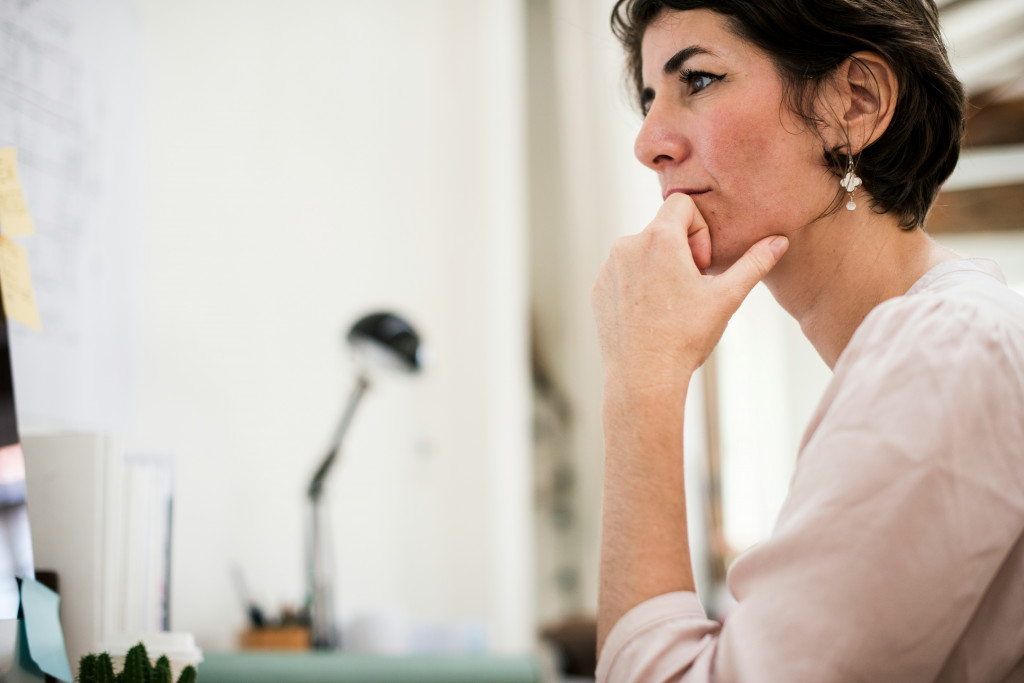 A woman looks thoughtfully into the distance while at her desk, representing the concentration difficulties and brain fog that can lead women to explore testosterone therapy during perimenopause.